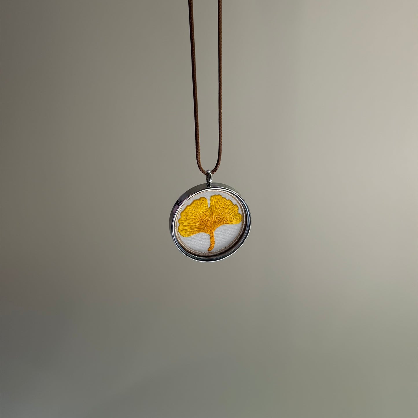 Display of a golden embroidered ginkgo leaf pendant
