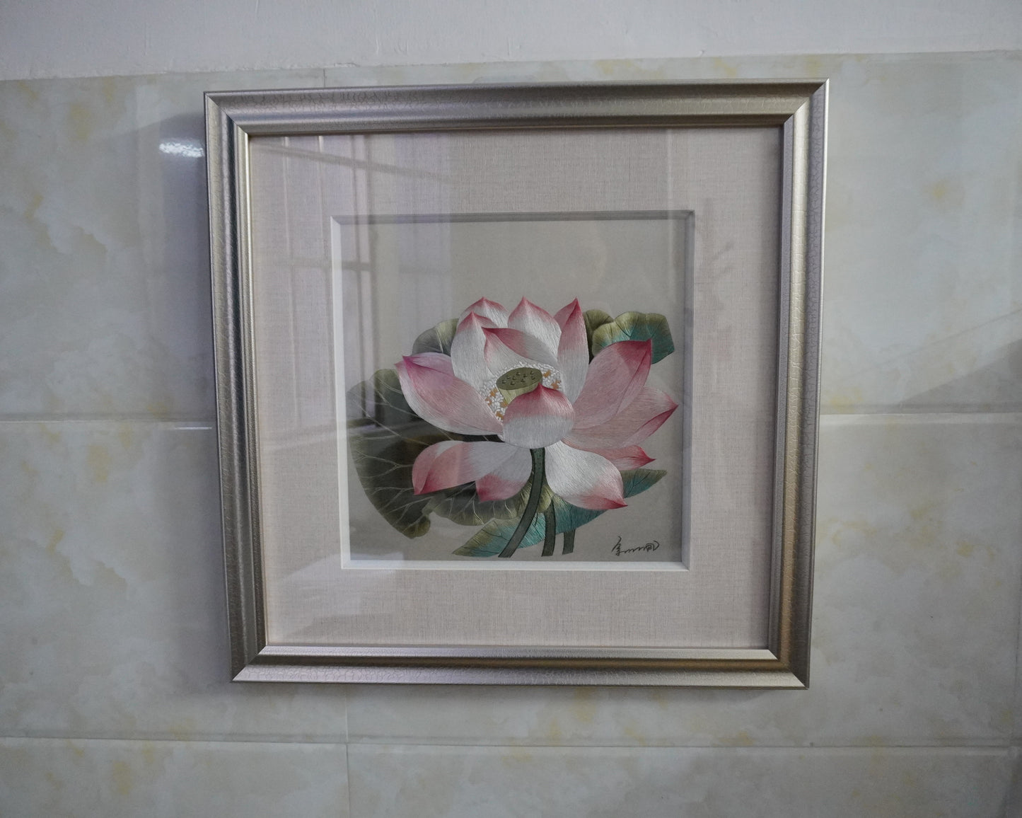 Framed lotus embroidery hanging on  wall. Hand-embroidered silk art in silver frame, 50.5cm square with glass.