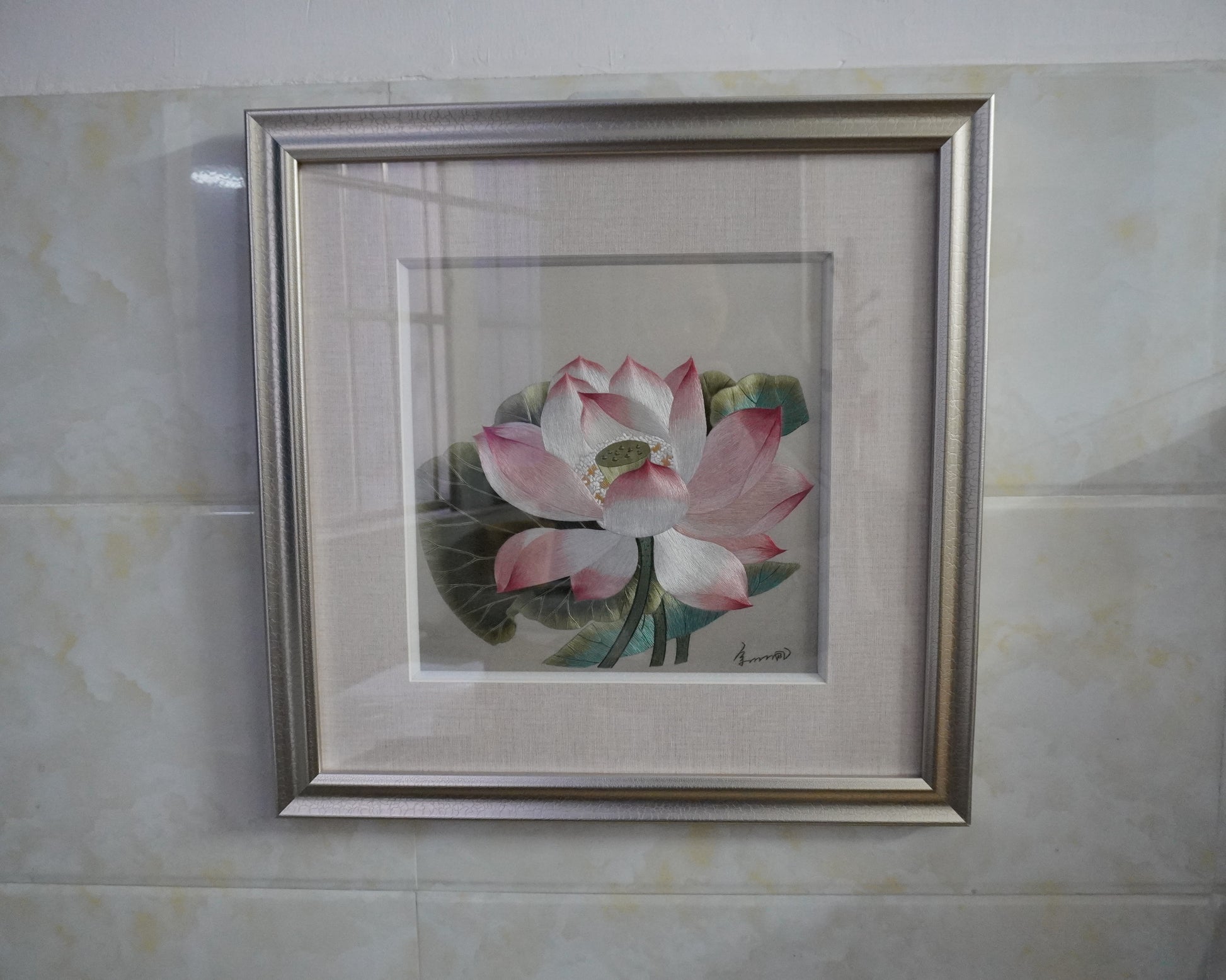 Framed lotus embroidery hanging on  wall. Hand-embroidered silk art in silver frame, 50.5cm square with glass.