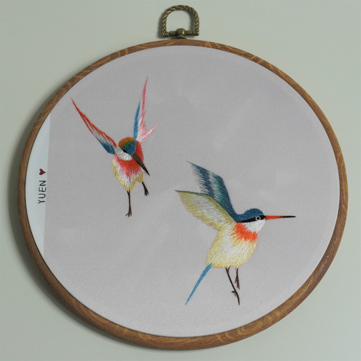 Colorful hummingbird hand-embroidery hoop art on round faux-wood frame