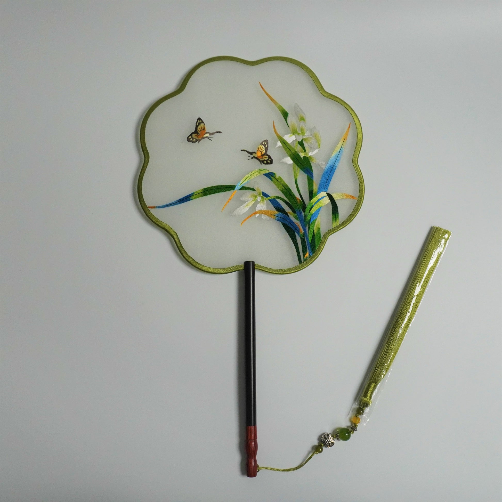 Double-sided embroidery orchid and butterfly on silk gauze fan. Plum blossom shaped frame with redwood handle, jade bead tassel.