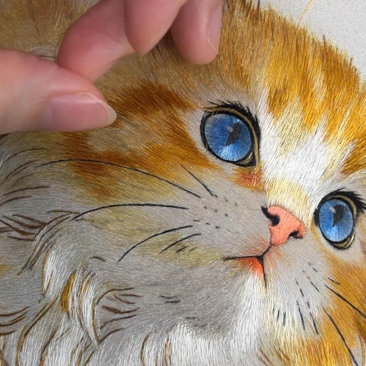 Work in progress of hand-embroidered golden cat on embroidery frame