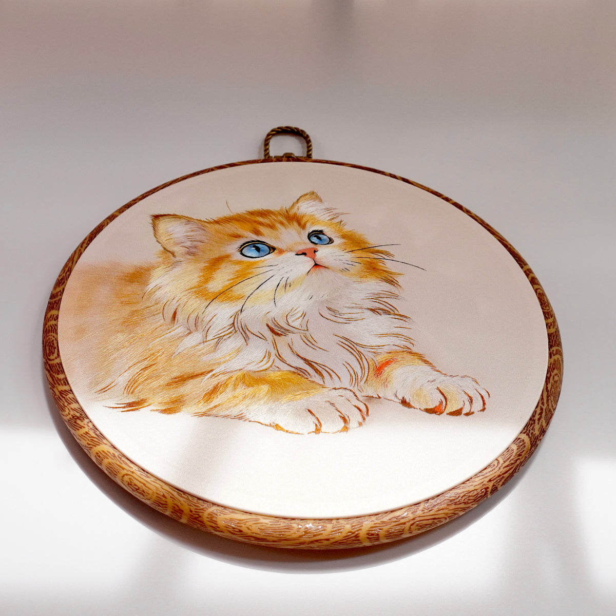 Side view of cat embroidery hoop showing faux-wood frame thickness