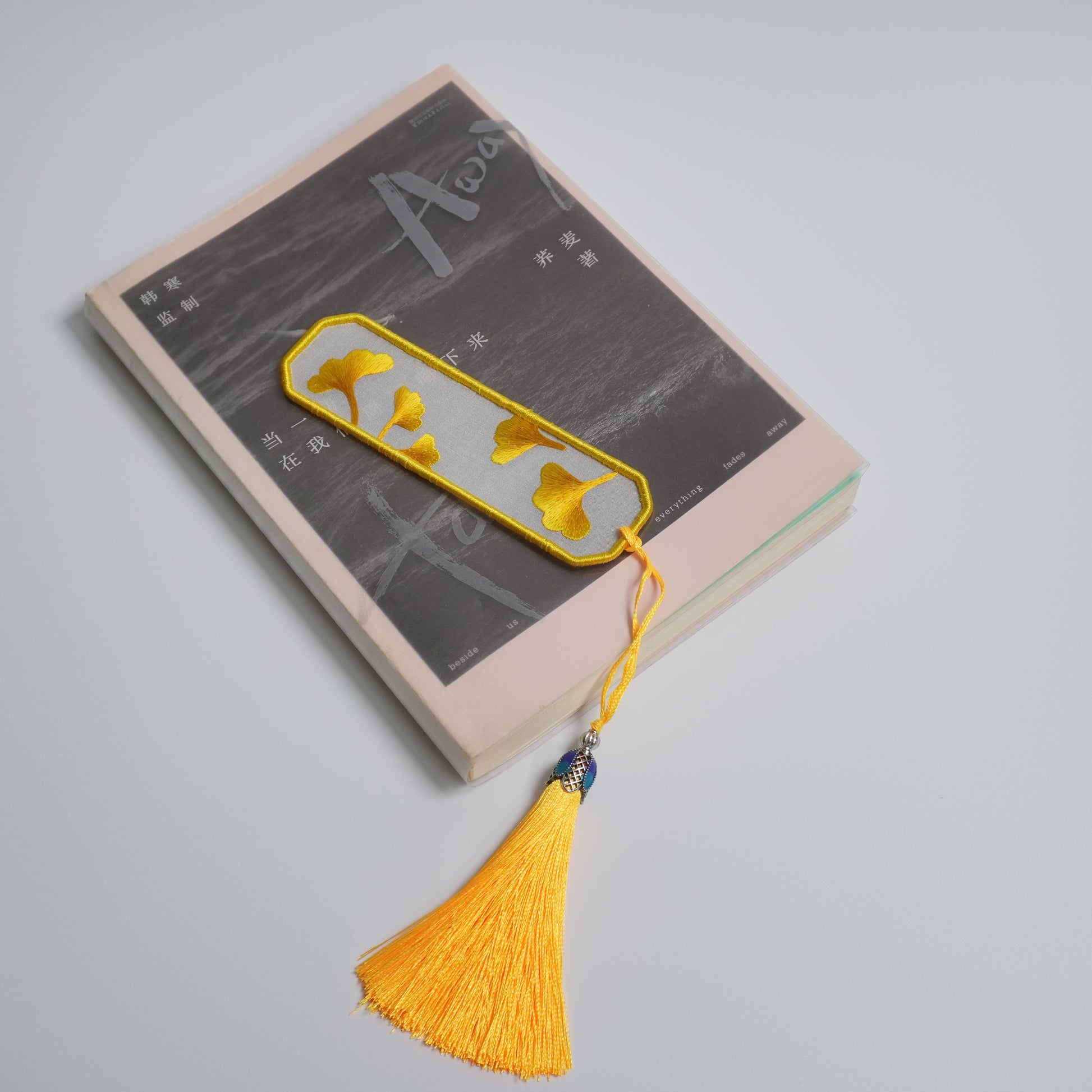 Hand-embroidered ginkgo leaf bookmark on silk with olive yellow tassel. Traditional Chinese embroidery craft.
