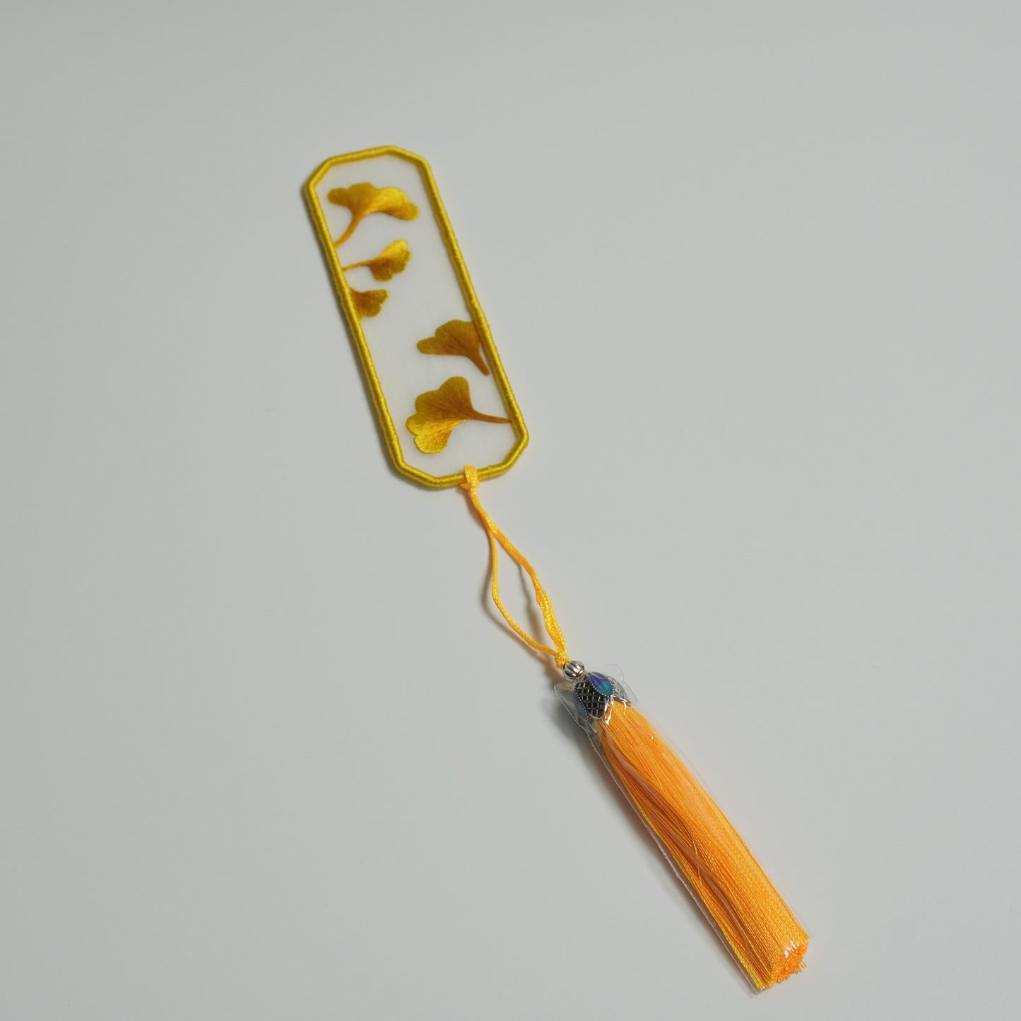 Hand-embroidered ginkgo leaf bookmark on silk with olive yellow tassel. Double-side emrboidery.