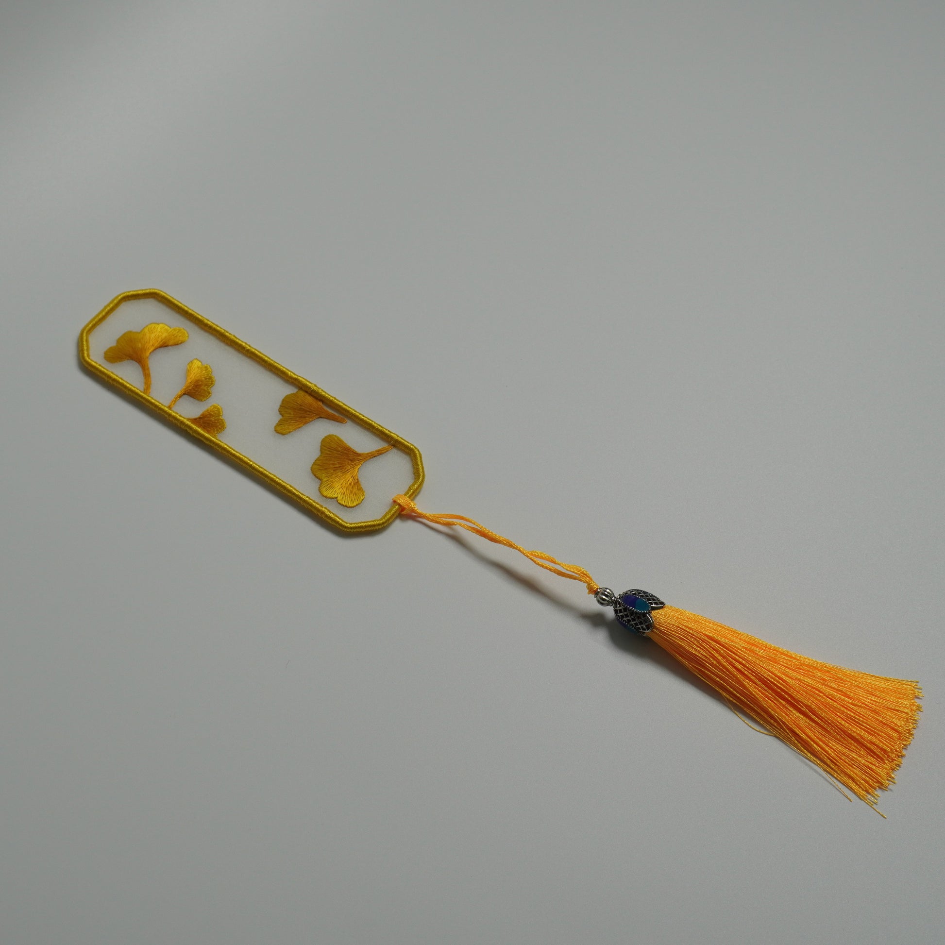 Hand-embroidered ginkgo leaf bookmark on silk with olive yellow tassel. Chinese craft of double-side embroidery.