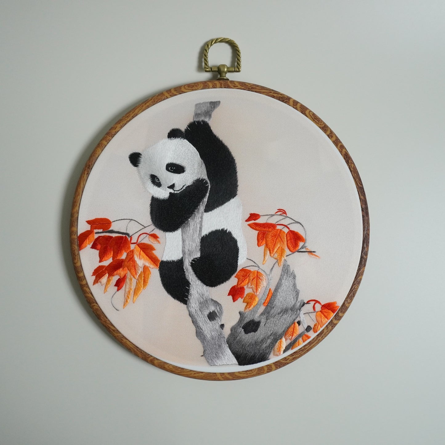 Hand-embroidered panda climbing maple tree branch on round faux-wood hoop. 20cm silk embroidery wall art. Chinese craft.