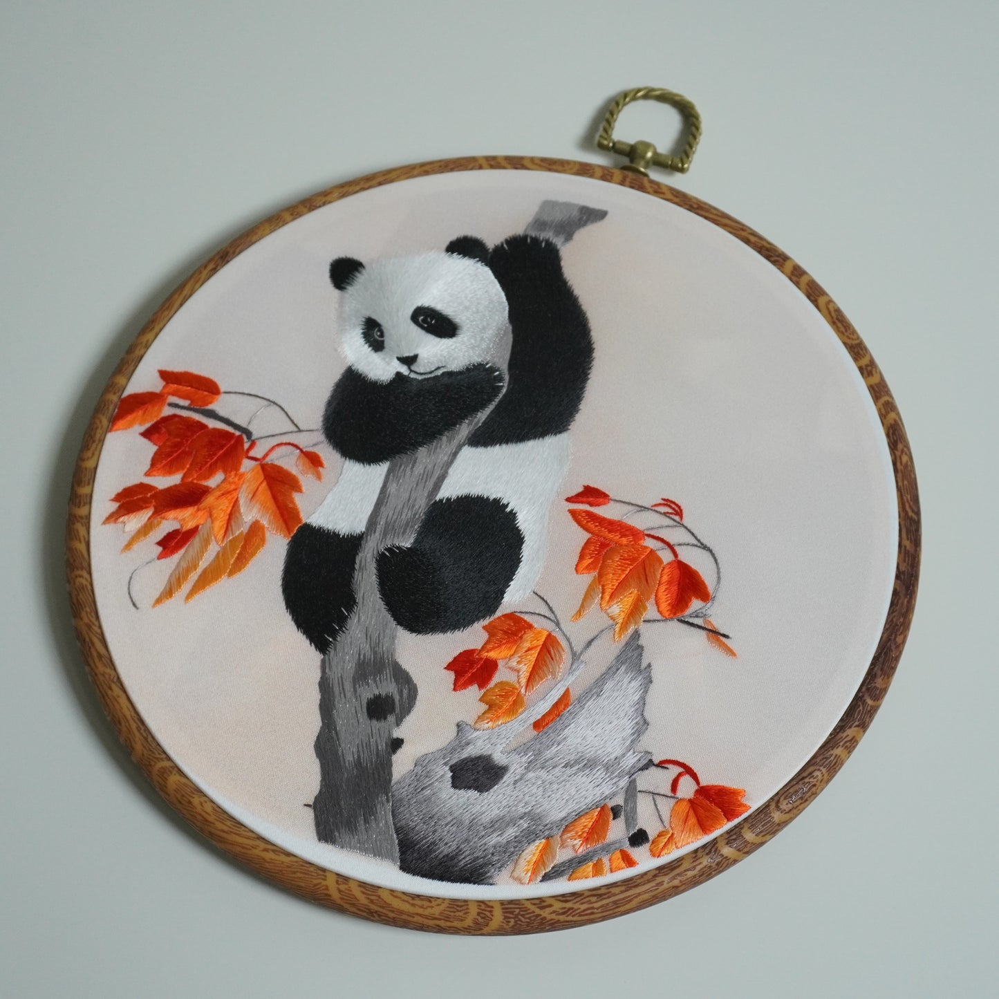 Hand-embroidered panda climbing maple tree branch on round faux-wood hoop. 20cm silk embroidery wall art with hook.
