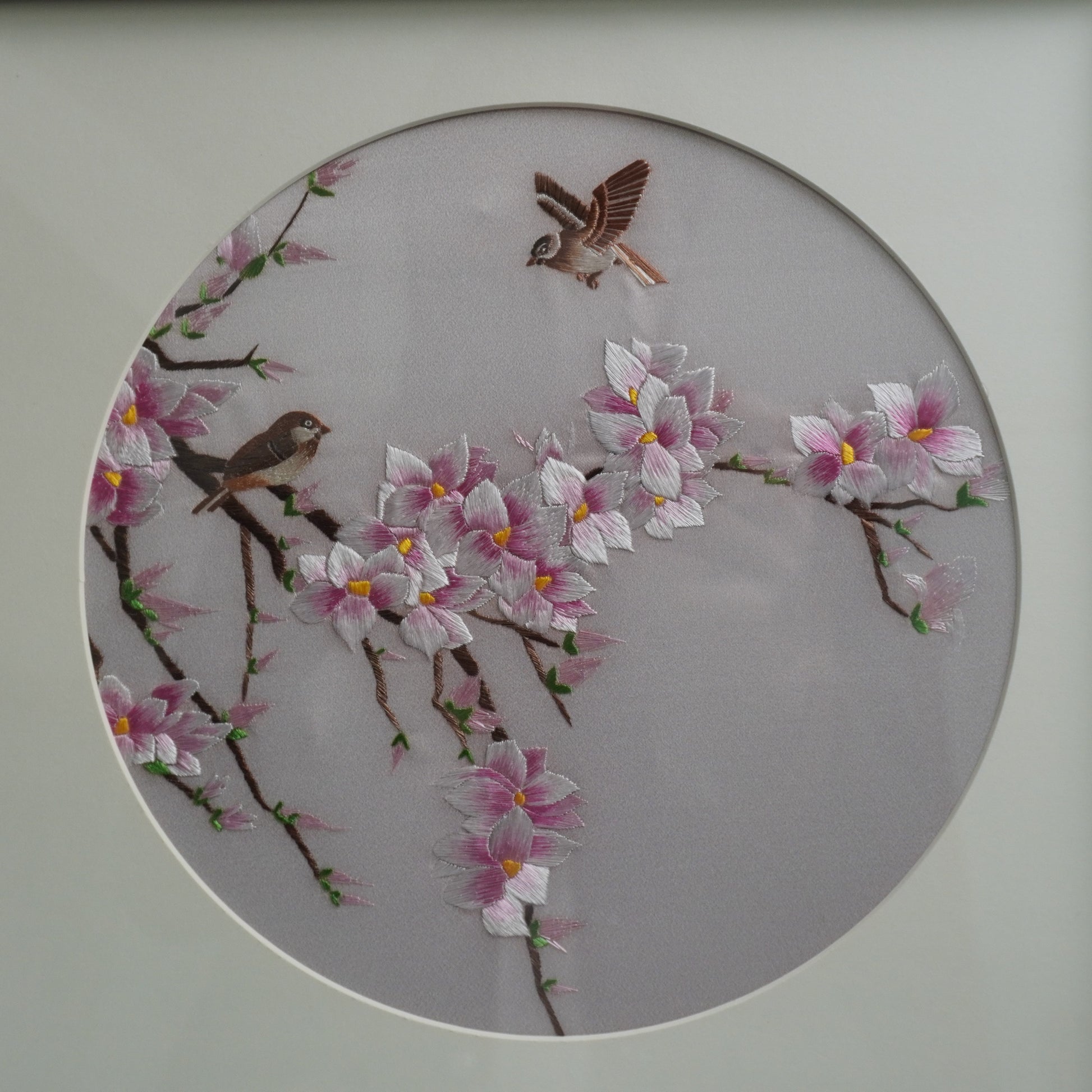Close-up of hand-embroidered magnolia and birds artwork